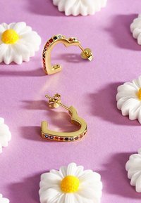 Guld hoops øreringe med et buet design, der prydes af farverige ædelstensakcenter i rød, blå og pink langs kanten.