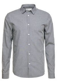 Chemise à carreaux noir et blanc avec un col, des manches longues et une texture de tissu lisse. Présente des boutons blancs sur le devant.