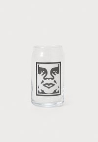 Clear glass cup featuring a black and white graphic of a face within a rectangular frame, smooth texture, and slightly curved shape.