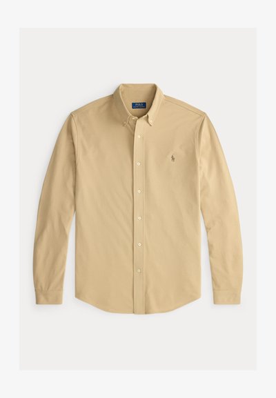 Camisa beige de manga larga con botones, cuello abotonado y pequeño logo de Polo Ralph Lauren bordado en el pecho izquierdo.