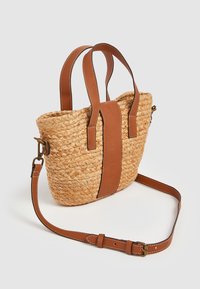 Vävd halmhandväska med ljusbruna läderdetaljer, två korta handtag och en justerbar axelrem. Slät textur med präglad varumärkesdetalj.
