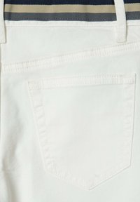 Vita tygshorts med en bakficka med en spetsig design och synlig sömnad, kompletterat med ett randigt midjeband.