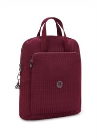 Burgundy ryggsäck gjord av strukturerad tyg, med två handtag, en zippered framficka och en logotypapplikation på framsidan.