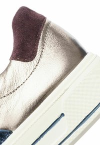Nazouvací bota s metalicky stříbrným koženým svrškem, vínově červenou semišovou patní částí a bílou texturaovanou gumovou podrážkou s modrým akcentem.
