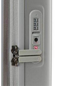 Valigia rigida argentata con combinazione di lucchetto, sistema di sicurezza approvato TSA, doppie cerniere e design a superficie texturizzata.