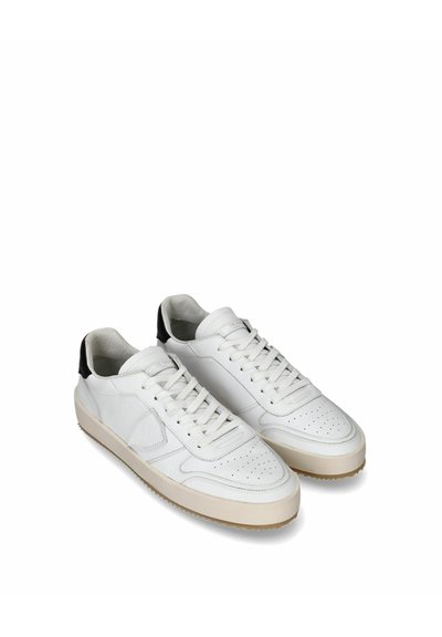 Baskets blanches en cuir avec une finition texturée, un design perforé et des accents noirs au niveau du talon. Elles sont dotées de lacets plats et d'une semelle beige.
