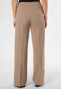 Beige weite Hose mit elastischem Bund, zwei Gesäßtaschen und glatter Textur. Keine sichtbaren Beschläge oder Muster.