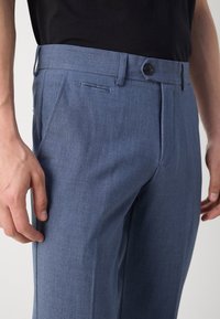 Pánské modré kalhoty vyrobené z lehké tkaniny s plochým předním dílem, postranními kapsami, poutky na opasek a jednobuttonovým zapínáním.