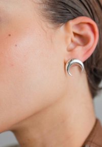 Boucles d'oreilles en argent en forme de croissant de lune, au design courbé, finition polie, fixées au lobe, mettant en valeur une texture lisse et une surface réfléchissante.