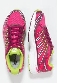 Ljusa rosa löparskor med en ventilerande ovandel, vinröda detaljer, vit mellansula och grön foder. Har sneda ränder och texturerad sula.