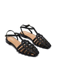 Sandalias negras trenzadas con un diseño de crisscross, tacón plano y correa para el tobillo ajustable; fabricadas con material sintético y con una plantilla suave.