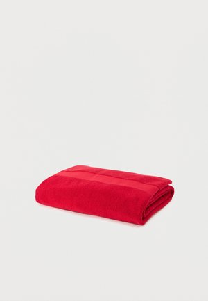 Bright red folded bath towel with a textured band on a plain white background.