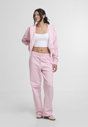 Lys rosa, kort hoodie med glidelås foran og bukser med snøring i matchende farge. Glatt tekstur og avslappet passform.