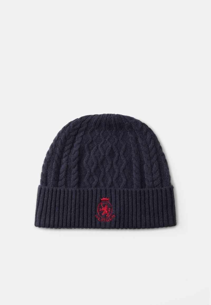 Marine gebreide beanie met kabelpatroon, geribbelde manchet en rood geborduurd logo aan de voorkant. Zachte textuur, geschikt voor koud weer.