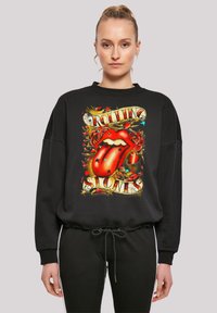 Schwarzer Pullover mit einem großen, farbenfrohen Motiv, das rote Lippen, Rosen und den Schriftzug "Rolling Stones" im Vintage-Stil zeigt. Locker sitzendes Design.