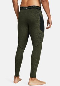 Olive green athletic leggings made of textured fabric, featuring a black side panel and an elastic waistband with logo at the top.