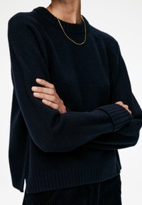 Marineblauer Pullover mit geripptem Rundhalsausschnitt und langen Ärmeln, ausgestattet mit strukturierten Details an den Schultern und einem gerippten Saum. Weiches Strickmaterial.
