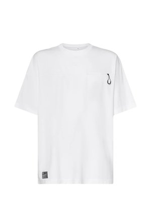 T-shirt bianca a maniche corte con un piccolo cursore nero sul petto in alto a destra e un'etichetta rettangolare nera vicino all'orlo inferiore.