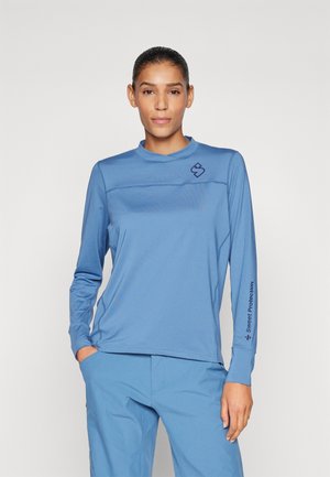 Long-sleeve athletic shirt in light blue, made of smooth fabric. Features a round neckline and logo on the chest with text on the sleeve.