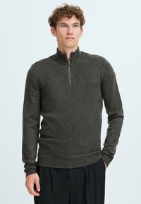 Mørkegrå zip-neck genser laget av et mykt strikket stoff. Har lange ermer og ribbestrikkede mansjetter og nederkant. Minimalistisk design, ingen mønster.