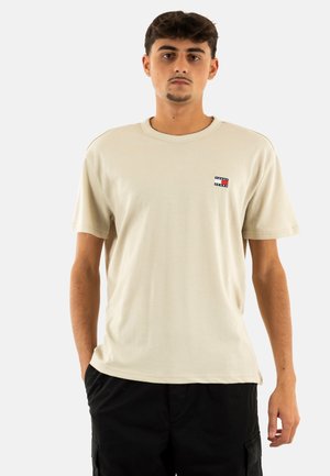 Beige T-Shirt mit kurzen Ärmeln aus Baumwolle, mit einem kleinen Markenlogo auf der linken Brust und einem lässigen Schnitt.