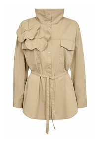Chemise beige avec col montant, boutons sur le devant, deux poches poitrine, et un grand accent floral sur l'épaule gauche ; taille cintrée avec ceinture pour la forme.