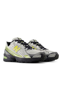 Sportovní boty s šedým a bílým síťovaným svrškem, doplněné o neonově žluté detaily. Tmavé tkaničky a texturované černé gumové podrážky.