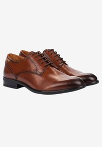 Chaussures habillées en cuir marron avec une finition lisse, bout arrondi et six œillets, dotées d'une semelle en caoutchouc noire et de accents matériels minimaux.