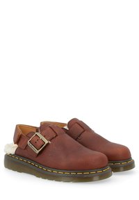 Bruine leren klompen met een gespsluiting, een fluffy voering en een dikke, gestructureerde zool met gele stiksels.