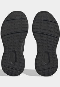 Svarta sportskor med sulor som har texturerade mönster och spår, med en cirkulär logotyp på undersidan och texten "NON MARKING".