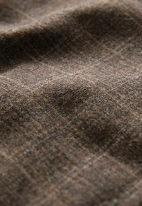 Brown textured fabric with a subtle pattern, featuring soft fibers and a slightly crinkled appearance, conveying a warm, layered look.