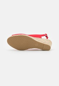 Sandalo wedge espadrille rosso con tacco rivestito in juta e suola in gomma. Presenta una sottile cinghia alla caviglia con dettaglio in metallo argentato.