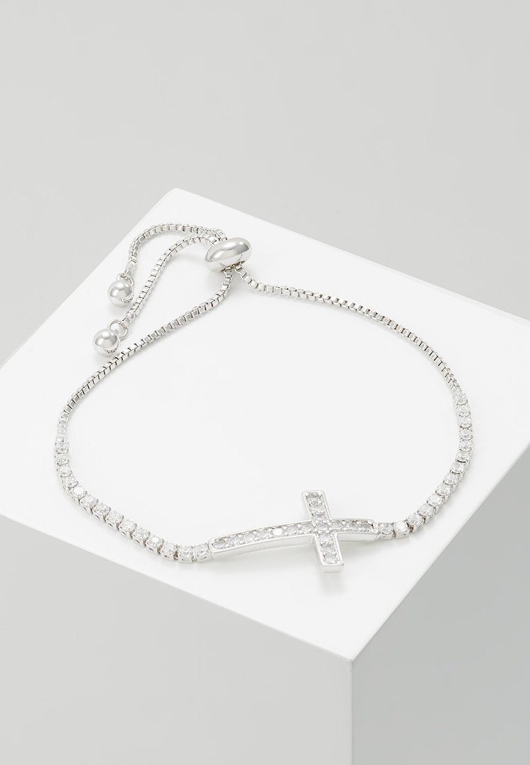 Sidabrinė apyrankė su kryžiaus dizainu, papuošta skaidriais brangakmeniais, papildyta lanksčia grandine ir reguliuojamu užsegimu.