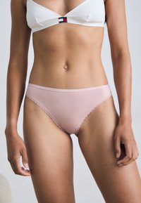 Roza bombažna bikini hlačke s valovitimi robovi in pasom z logotipom. Gladka tekstura, preprost dizajn in prileganje.