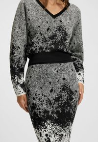 Set di maglione e gonna a maglia con motivo a spina di pesce in bianco e nero, con una finitura testurizzata e una vita nera.