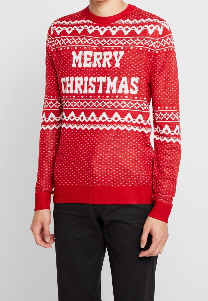 Rode gebreide trui met witte "MERRY CHRISTMAS" tekst, geometrische patronen, en geribbelde boorden en zoom. Gestructureerde stof met een feestelijk thema.