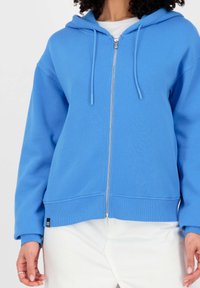 Lichtblauwe rits hoodie met een capuchon, lange mouwen en een ribgebreide zoom. Voorzien van koordjes en een klein label aan de onderkant aan de linkerzijde.