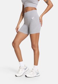 Sive atletske kratke hlače iz mehkega, elastičnega materiala, z visokim pasom in majhnim belim logotipom spredaj.