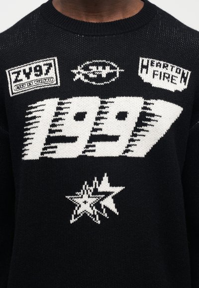 Černý pletený svetr s bílým nápisem a motivy: "1997", logy a hvězdný vzor. Kulatý výstřih, texturovaná látka, casual styl.