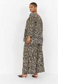 Zebra-prindiga kaherealine komplekt, mis koosneb lahtisest toppist ja pikast seelikust. Valmistatud kergest kangast, millel on sujuv tekstuur ja muted värvid.