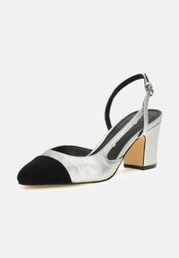Scarpa slingback argento e nera con tacco basso, caratterizzata da una tomaia metallica lucida e una punta in morbido suede nero.