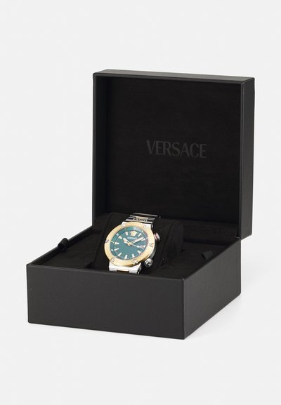 Versace sat sa crnom kutiji, nehrđajući čelik i zlatni okvir, tirkizna brojčanik s oznakama sati, srebrna narukvica, prikazuje luksuzni dizajn.