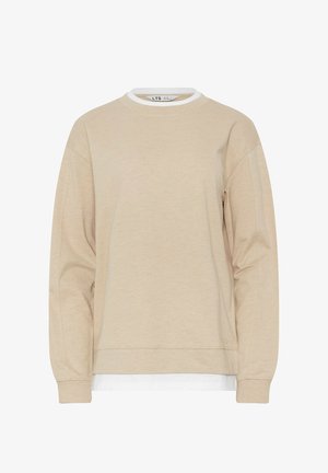Beige sweatshirt met lange mouwen en ronde hals, gedragen over een wit shirt, afgebeeld tegen een effen witte achtergrond.