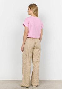 Lyserød bomulds-T-shirt med opsmøgede korte ærmer, parret med beige stribede brede cargo-bukser med sidelommer og elastisk talje.