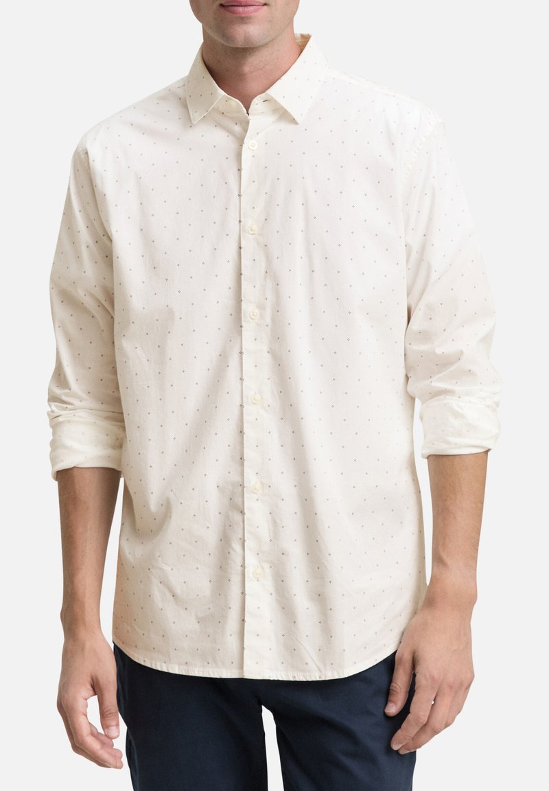 Helle kremfarbene Button-Up-Hemd mit kleinem braunen Punktmuster, langärmelige, hochgerollte Ärmel, aus Baumwollmaterial, spitzen Kragen und vorderer Knopfleiste.