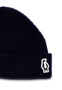 Cappello di lana blu navy lavorato a maglia con una spessa texture a coste e un piccolo logo a patch di un pinguino bianco sul davanti.
