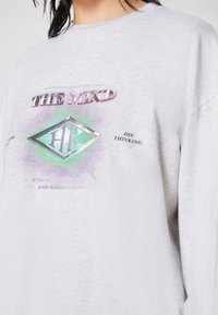Grå bomullströja med en färgglad grafik med texten "THE MIND" och en diamantlogotyp, rund halsringning och långa ärmar.