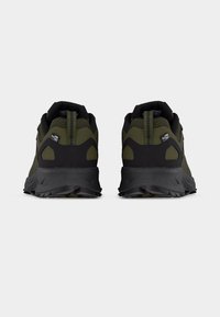 Ζεύγος παπουτσιών για τρέξιμο σε μονοπάτια σε ελιά πράσινο και μαύρο, που φαίνονται από πίσω με υφή στις σόλες και θηλιές για τράβηγμα, σε λευκό φόντο.