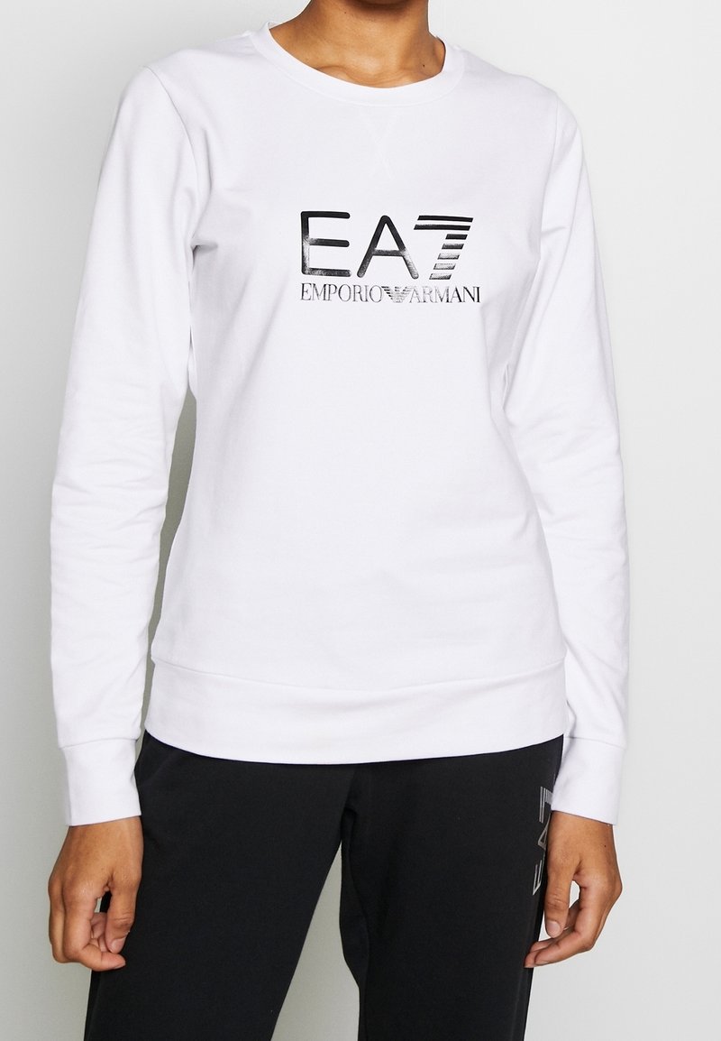 Vit sweatshirt i bomull med långa ärmar. Har en reflekterande svart logotyp "EA7 Emporio Armani" på framsidan och ribbade muddarmar.