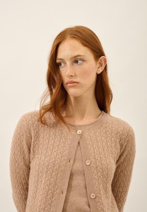 Hellbraune Strickjacke mit einem Zopfmuster, runder Ausschnitt und fünf Knöpfen vorne. Weiche Textur, lange Ärmel.